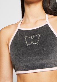 Top corto gris de halter con ribete rosa, que presenta un diseño de mariposa hecho de rhinestones en el pecho. Textura suave, diseño casual.