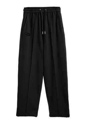 Pantalones jogger negros de corte holgado con cintura elástica, cordón, bolsillos laterales y una pequeña etiqueta rectangular con logo en el muslo izquierdo.