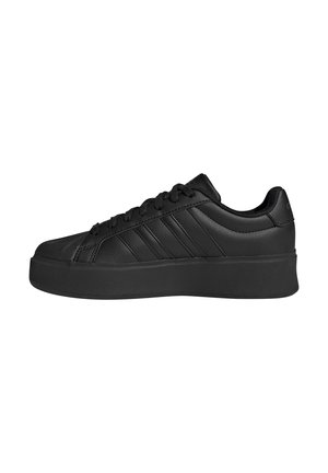 Schwarzer flacher Sneaker mit dicker Sohle, Schnürung vorne und drei seitlichen Streifen, im rechten Profil vor weißem Hintergrund dargestellt.