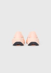 Chaussures de sport en mesh rose avec un dos texturé, dotées d'une semelle rembourrée et d'une semelle extérieure en caoutchouc noir pour plus de traction.
