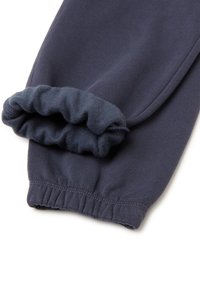 Navy modré tepláky s texturovaným elastickým lemem na kotníku a hladkým, lehkým materiálem. Rovný střih bez kapes.