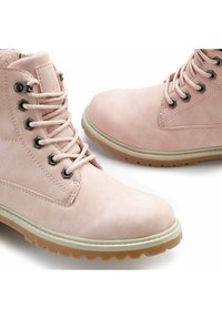 Botas de tobillo sintéticas rosas con ojales de metal, superficie texturizada, suela blanca y suela de goma beige claro. Cuenta con puntera redonda y cordones.