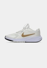 Scarpa da corsa Nike bianca con tomaia in rete, logo swoosh dorato, colletto imbottito e suola testurizzata in contrasto tra nero e bianco.