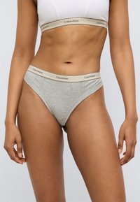 Γκρι βαμβακερό σλιπ τύπου tanga με μαλακή ελαστική μέση που φέρει το λογότυπο Calvin Klein. Ο σχεδιασμός τονίζει μια μίνιμαλ κοπή και εφαρμοστή γραμμή.