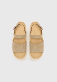 Beige suede szandál két széles pánttal és egy könnyű krémszínű talppal. Állítható csattal rendelkezik.