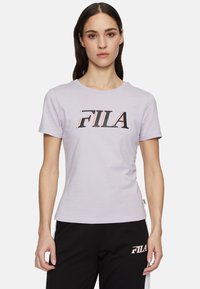 Camiseta de algodón de manga corta en color lavanda, con un destacado logotipo "FILA" en negro y rosa en el pecho. Diseño clásico de cuello redondo.
