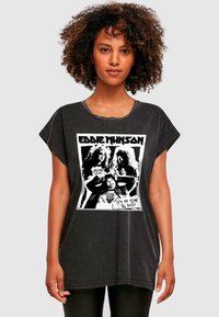 Čierne oversized tričko s grafickým potlačou s postavou Eddieho Munsona a textom. Bavlnená látka s distressed povrchom a vyhrnutými rukávmi.