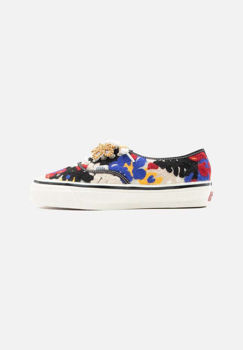 Χαμηλό sneaker Vans με λευκή σόλα, πολύχρωμο floral μοτίβο σε μπλε, κόκκινο, κίτρινο και μαύρο και στολισμό με χάντρες στα κορδόνια, σε λευκό φόντο.