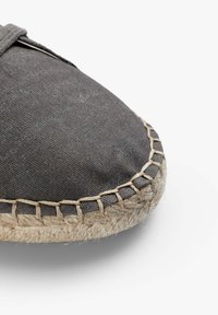 Grå lærredssko med en espadrille-stil jute reb-sål. Har syet detaljering langs kanten. Flad, rund tå-design.
