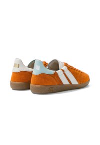 Paire de baskets en daim orange avec des bandes blanches, des accents bleu clair et blanc au talon, et des semelles en caoutchouc marron texturé sur fond blanc.