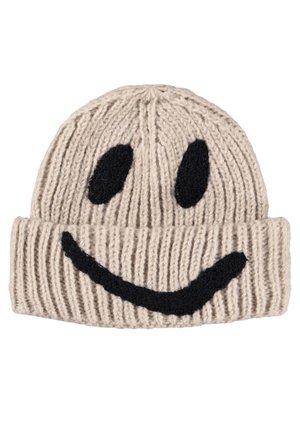 Beige strikket hue med sorte broderede øjne og en bred smilende mund på den foldede kant.