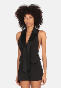 Gilet nero su misura con scollatura a V profonda e colletto in satin. Presenta un design senza maniche, tasche frontali e un dettaglio annodato al collo.
