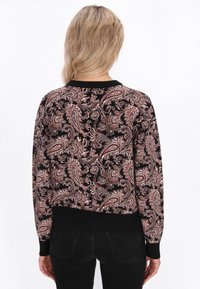 Maglione nero con un motivo paisley in rosa e beige. Presenta polsini e orlo a coste neri, con tessuto lavorato a maglia testurizzato.
