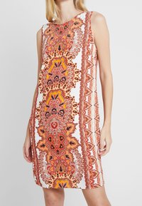 Ärmelloses Kleid mit einem komplizierten orange-rot Paisley-Muster auf weißem Hintergrund, einem einfachen runden Ausschnitt und lockerer Passform.
