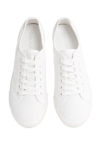 Paar weiße, niedrige Schnürsneaker mit Gummisohlen und dezenten Markenkennzeichnungen auf den Innensohlen, von oben auf weißem Hintergrund betrachtet.