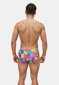 Swim briefs featuring a colorful patterned design reminiscent of building blocks, made of stretchy material, with a snug fit.