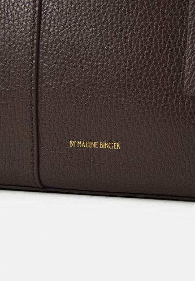 Pruun nahkse viimistlusega kott. Omab kuldset logo, sujuvat tikandit ja struktureeritud disaini.