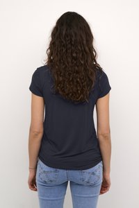 Sötétkék, rövid ujjú póló, karcsú fazonnal és sima textúrával, világoskék farmernadrággal, amely klasszikus zsebkialakítással rendelkezik.