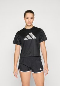 Black athletic t-shirt with a textured white Adidas logo and black shorts with white trim. Both items are designed for comfort and performance.