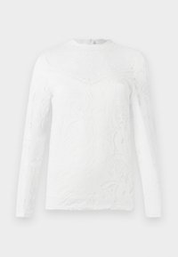 Top blanc à manches longues en tissu de dentelle avec des motifs floraux complexes, un col rond et une fermeture au dos. Fini doux et texturé.