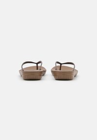 Brune flate sandaler med tynne stropper og en teksturert såle. Designet har en minimalistisk form og glatt overflate, ideelt for hverdagsbruk.