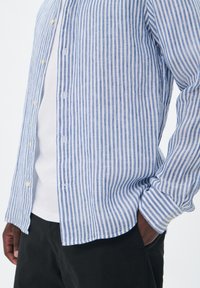 Camicia a righe blu e bianca, realizzata in tessuto leggero, con colletto, maniche lunghe e orlo curvo.