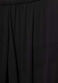 Țesătură neagră plisată cu o textură netedă. Talie elastică în partea de sus. Linii verticale subtile creează un fald elegant.