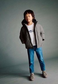 Gray puffer jacket with a hood, white T-shirt with blue text, blue jeans, gray shoes. Smooth texture, casual fit, and neutral color palette.