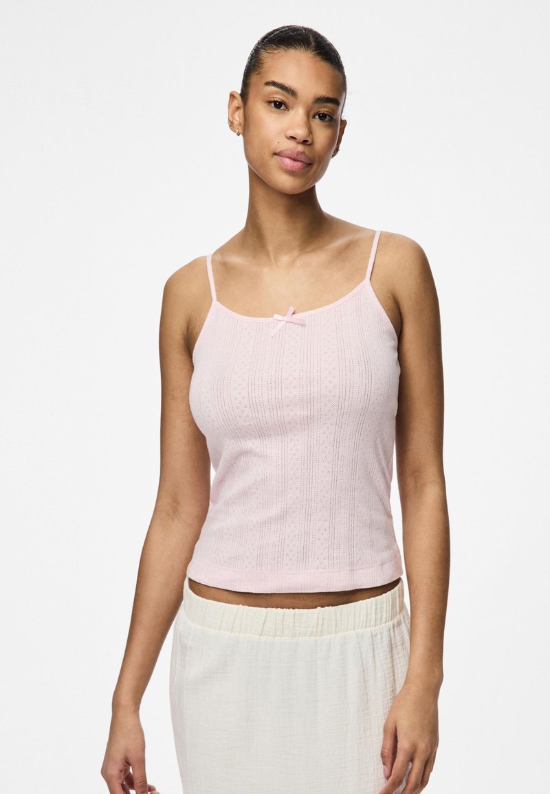 Světle rů�žová tílko s tenkými ramínky, s malým detailem mašle a texturovaným vzorem vertikálních linií a kosočtverců.