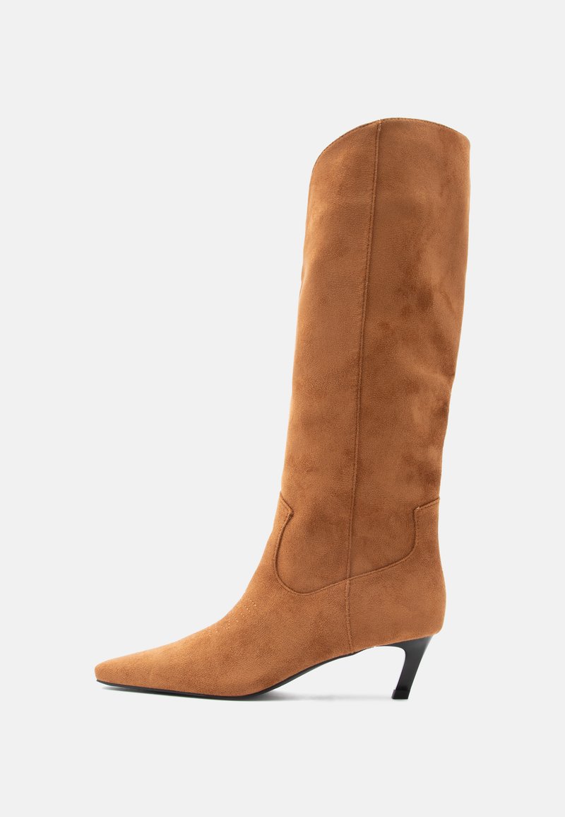 Botte haute en daim marron jusqu'au genou avec un bout pointu et un petit talon conique. Présente une texture lisse et un détail de couture subtil sur le côté.