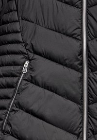 Gilet matelassé noir avec un motif en losange, doté d'une fermeture éclair argentée et d'une poche latérale, fabriqué en tissu lisse et déperlant.