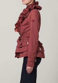 Gerimpeld bordeauxkleurig jack met een ceintuur in de taille, lange mouwen en gegolfde manchetten. Kenmerken omvatten gelaagde ruffles aan de voorkant en logo-accenten.