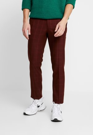 Burgundowe spodnie w kratę o slim fit, z wzorem w kratkę i kieszeniami bocznymi, zestawione z białymi butami sportowymi.