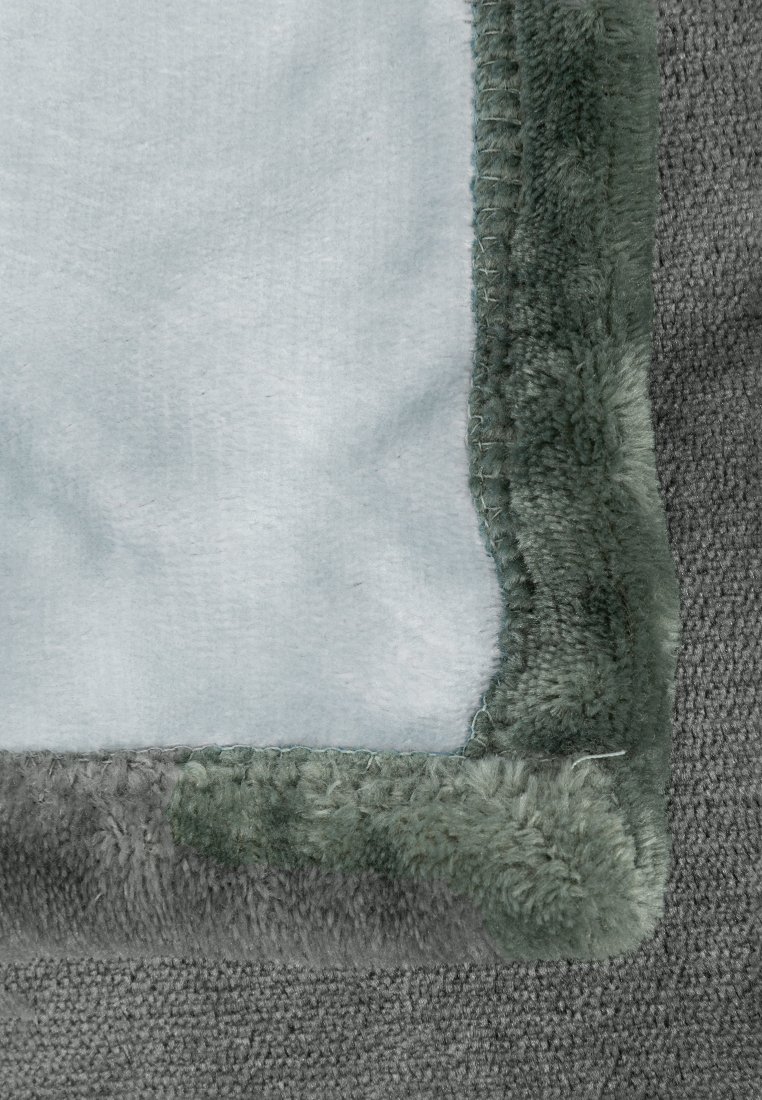 Couverture en peluche avec une texture grise douce, présentant un centre bleu clair lisse et des bords en polaire vert foncé.