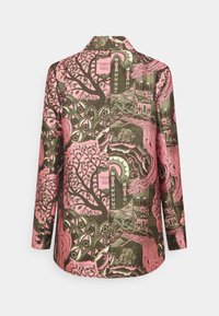 Camisa de manga larga colorida con un diseño gráfico en rosa y verde que incluye árboles, ojos y edificios. El material parece suave y ligero.