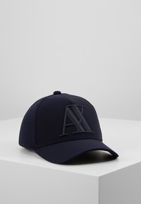 Cappellino da baseball blu con logo in gomma "AX" sul davanti. Design strutturato con corona arrotondata e visiera curvata, realizzato in tessuto liscio.