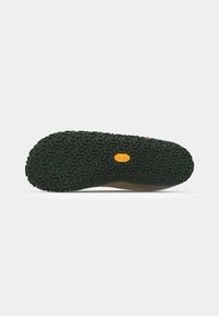 Suela de goma con un patrón texturizado; principalmente verde con un acento amarillo; diseñada para tracción y durabilidad.