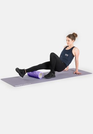 Lila Schaumstoffrolle auf einer grauen Trainingsmatte mit einer Person in schwarzen Leggings und einem dunklen Tanktop, die für eine Entlastungsübung mit der Rolle positioniert ist.