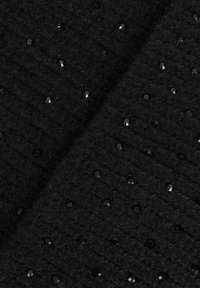 Tessuto in maglia nero con piccole perline nere lucide sparse uniformemente sulla superficie tessurizzata.