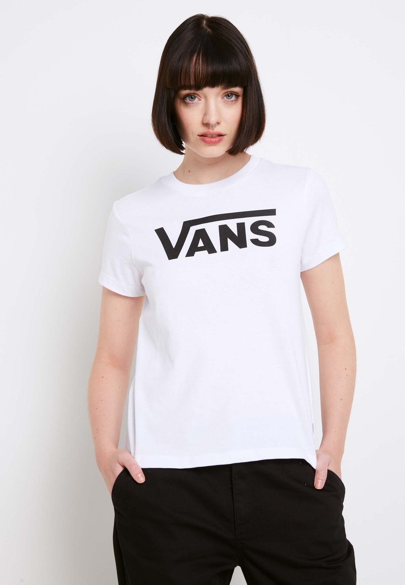 Bílé tričko s krátkým rukávem, na kterém je výrazné černé logo "VANS" napříč hrudí, vyrobené z měkkého bavlněného materiálu.