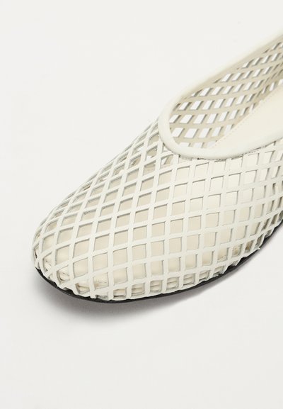 Hvide mesh slip-on sko med et krydsmønster, rund tå og sort gummisål. Blødt, fleksibelt materiale for komfort.