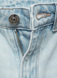 Jeans de mezclilla azul claro con un cierre de botón de metal, cremallera y costuras en color beige que contrastan en la cinturilla y las costuras de los bolsillos.