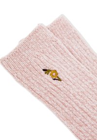 Calze a coste rosa pallido con un piccolo fiore giallo ricamato e foglie verdi vicino al bordo.