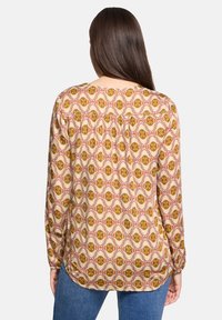 Blusa a maniche lunghe in tessuto leggero, caratterizzata da un motivo floreale con tonalità di senape, rosa e crema; vestibilità comoda con dettaglio arricciato sul retro.