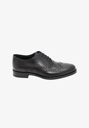 Zapato de vestir brogue de piel negra para hombre con diseño de ala, perforaciones decorativas y cierre de cordones, mostrado de perfil sobre fondo blanco.