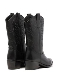 Botas de cowboy de cuero negro con patrones de costura intrincados, puntera afilada, tacón de bloque de altura media y pestañas de agarre en los lados.