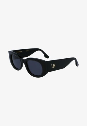 Occhiali da sole neri con una montatura massiccia e angolare, lenti scure e dettaglio del logo dorato sul lato. Finitura opaca e design elegante.