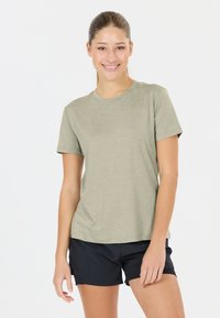 Licht olijfgroene T-shirt met korte mouwen, gemaakt van zachte stof en met een ronde halslijn, gecombineerd met zwarte sportshorts.