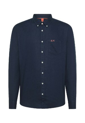 Camicia blu navy con bottoni e maniche lunghe, dotata di una tasca a toppa e un piccolo logo rosso sul petto. Realizzata in tessuto intrecciato.