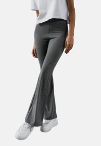 Szare rozszerzane spodnie wykonane z miękkiego materiału; średni wzrost z gładką teksturą; w połączeniu z białymi sneakersami.